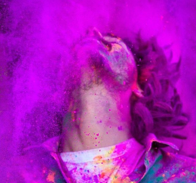 Young man covered in colored dye celebrating Holi festival in Jaipur, India.